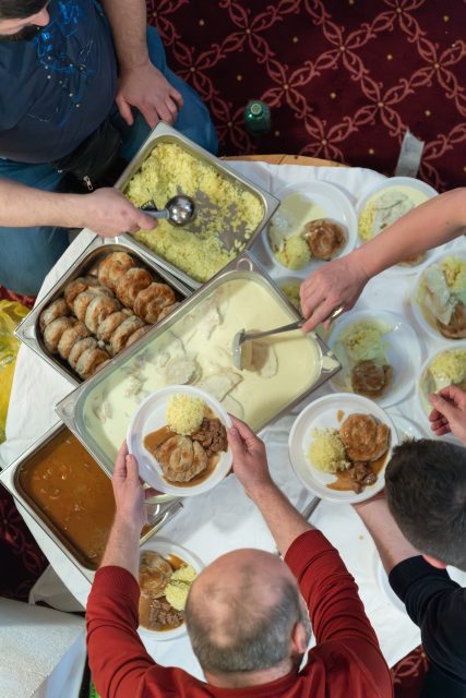 Top view of people serving food at a Mosque a communal meal during Ramadan before breaking the fast on Iftar dinner (26 of 28)