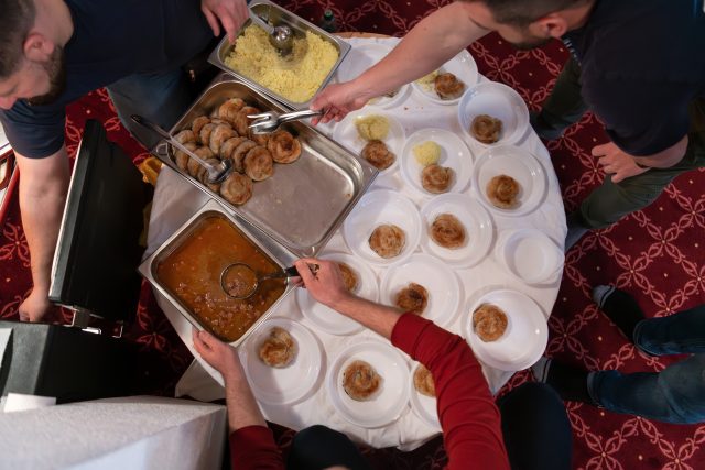 Top view of people serving food at a Mosque a communal meal during Ramadan before breaking the fast on Iftar dinner (18 of 28)