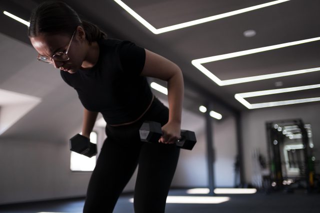 A woman is engaged in strength training in a well-lit gym