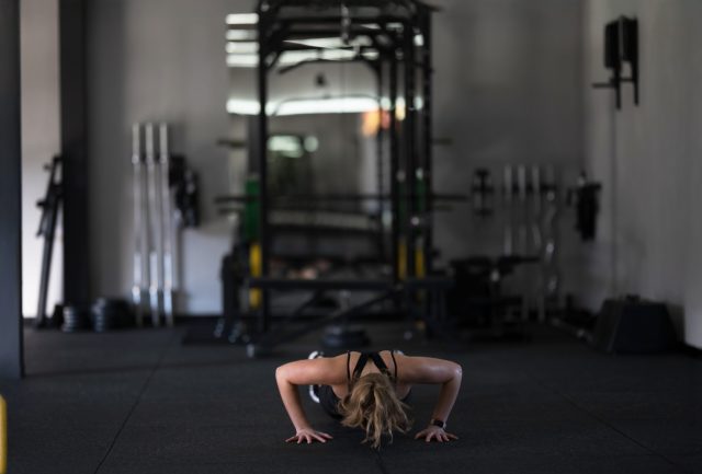 A focused athlete is engaged in push-ups on a black gym mat