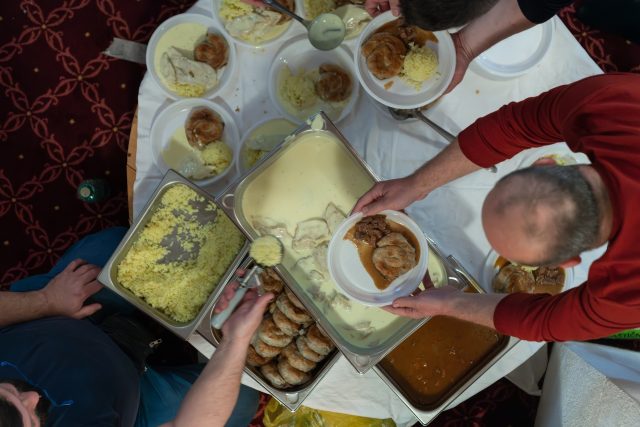 Top view of people serving food at a Mosque a communal meal during Ramadan before breaking the fast on Iftar dinner (24 of 28)