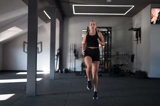A woman is engaged in a high knees exercise inside a contemporary gym