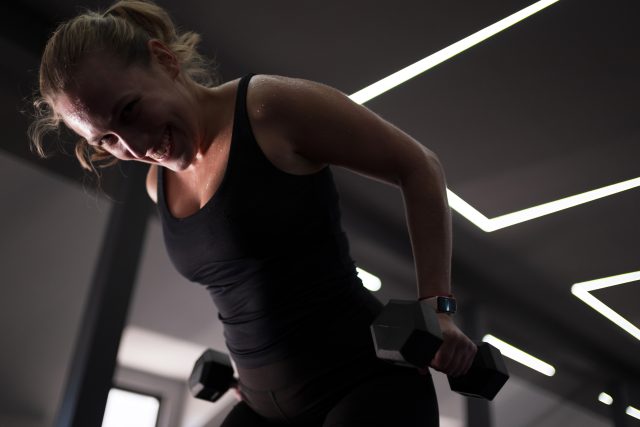 A woman engaged in weightlifting exercises in a stylish gym environment