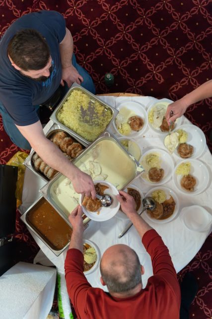 Top view of people serving food at a Mosque a communal meal during Ramadan before breaking the fast on Iftar dinner (21 of 28)