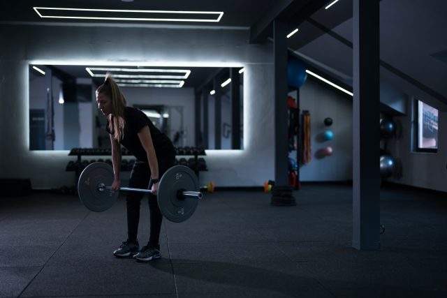 A woman is lifting a barbell in a well-equipped gym