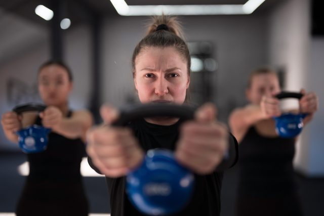 Women in a gym practice kettlebell exercises, showcasing determination and teamwork