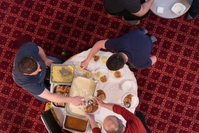 Top view of people serving food at a Mosque a communal meal during Ramadan before breaking the fast on Iftar dinner (20 of 28)