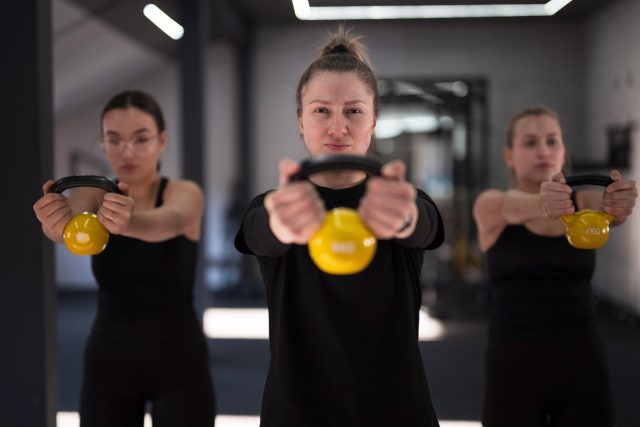 Group of women focus on their kettlebell workout in a gym