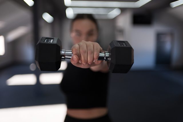 A fitness enthusiast engages in strength training with dumbbells in a well lit, modern gym