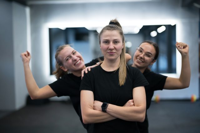 Group of women celebrate their strength and friendship in a gym