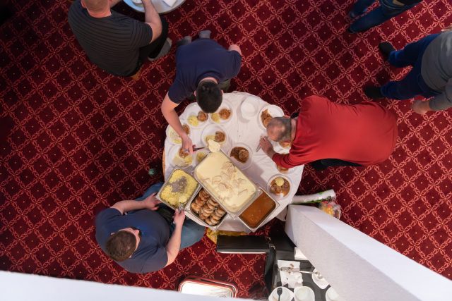 Top view of people serving food at a Mosque a communal meal during Ramadan before breaking the fast on Iftar dinner (19 of 28)