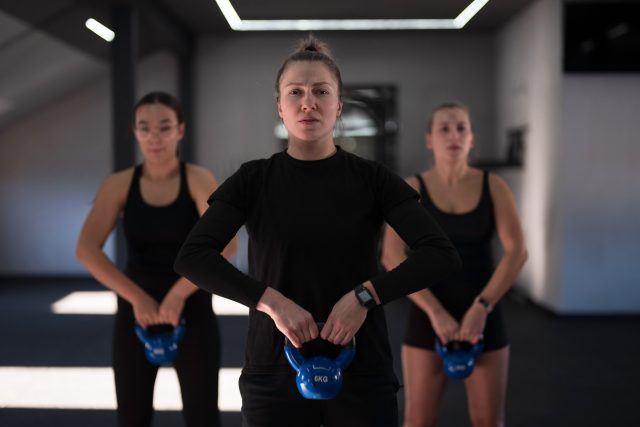 Group of women are engaged in a kettlebell workout in a sleek gym