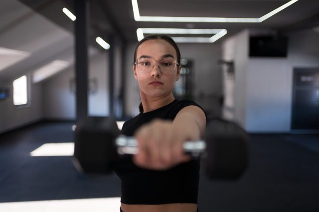 A young woman in a black top exercises in a bright fitness center