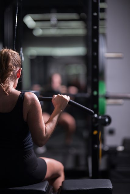 A woman is engaged in a seated cable row exercise at a gym