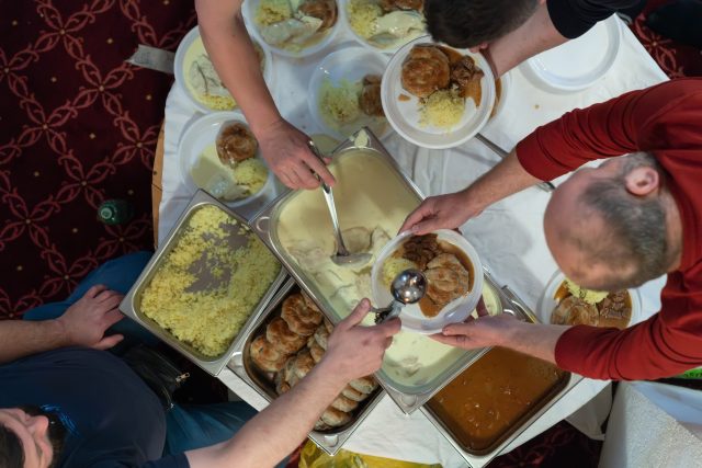 Top view of people serving food at a Mosque a communal meal during Ramadan before breaking the fast on Iftar dinner (25 of 28)