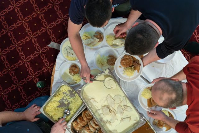 Top view of people serving food at a Mosque a communal meal during Ramadan before breaking the fast on Iftar dinner (27 of 28)