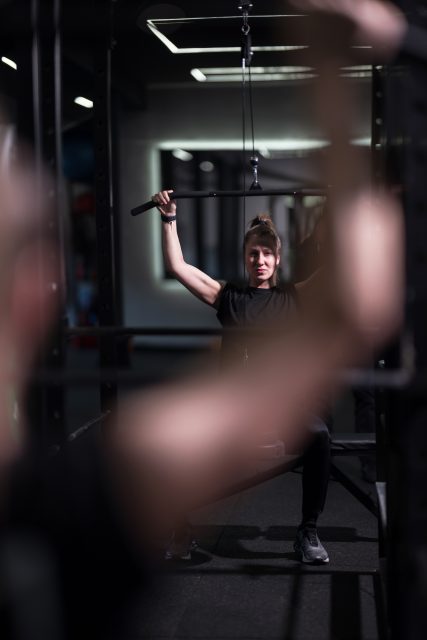 A dedicated woman exercises in a gym, lifting weights with concentration