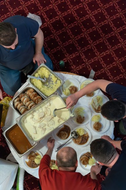Top view of people serving food at a Mosque a communal meal during Ramadan before breaking the fast on Iftar dinner (23 of 28)