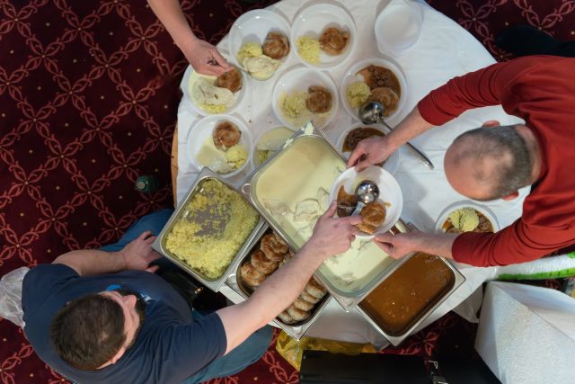 Top view of people serving food at a Mosque a communal meal during Ramadan before breaking the fast on Iftar dinner (22 of 28)