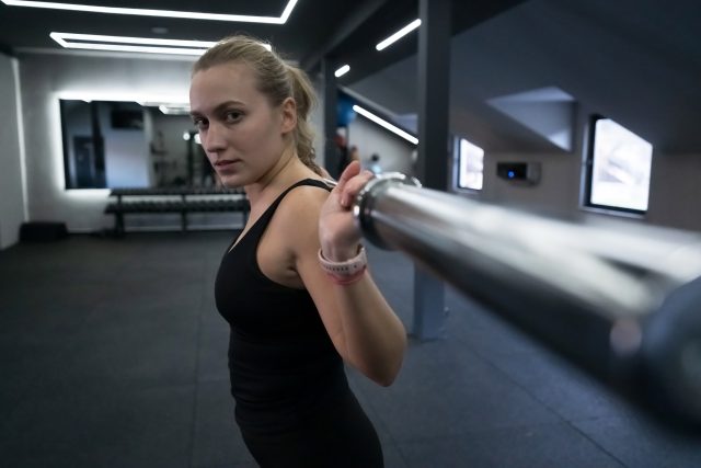 A dedicated woman is seen performing a weightlifting exercise in a well-lit gym